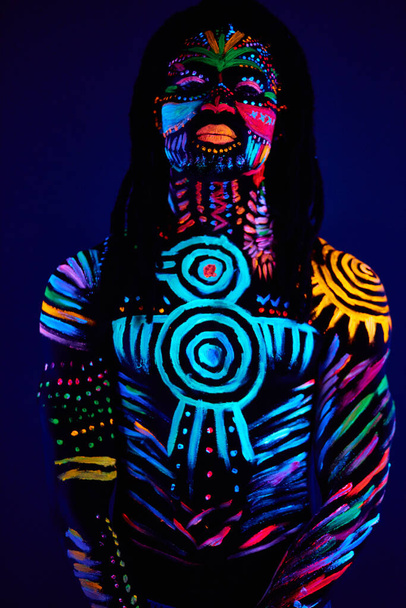 african man painted in fluorescent paint on face and muscular shirtless torso - Fotografie, Obrázek