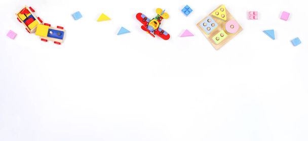 Baby kids toys banner background. Wooden educational geometric stacking blocks toy, constructor airplane, wooden train and blocks on white background. Top view - Foto, imagen