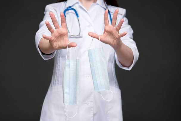 Lääkäri, jolla on lääketieteellinen kasvonaamio käsissä, osoittaa paniikkielettä.
. - Valokuva, kuva