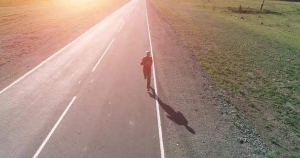 Lage hoogte vlucht voor sportieve man op perfecte asfaltweg - Video