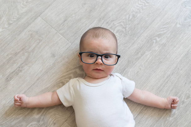 Pasgeboren baby met bril. Een jongetje in witte kleren. Mooi portret van een peuter. Grote ogen baby. Afstandsonderwijs. Afstandsonderwijs. - Foto, afbeelding