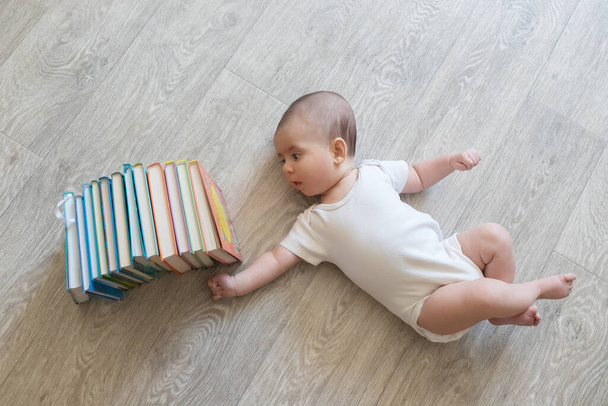 Vastasyntynyt vauva, jolla on kirjoja. Pieni poika valkoisissa ja sinisissä vaatteissa. Kaunis muotokuva taaperosta. Suurisilmäinen vauva. Etäopetus. Etäopiskelug
 - Valokuva, kuva