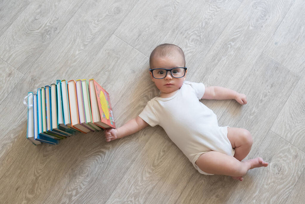 本のあるメガネの新生児。白い服と青い服の男の子。幼児の美しい肖像画。大きな目の赤ちゃん。遠隔教育。距離学習 - 写真・画像