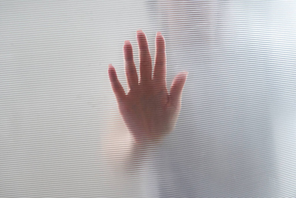 Verspreid silhouet van vrouwelijke handen door plastic - Foto, afbeelding