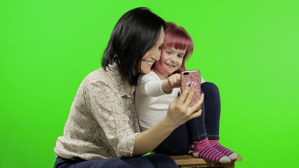 Mère, fille tenant, utilisant un téléphone intelligent parlant sur appel vidéo. Médias sociaux
 - Photo, image