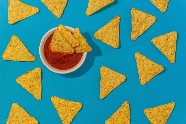 nachos chips met chili saus op een blauwe achtergrond close-up - Foto, afbeelding