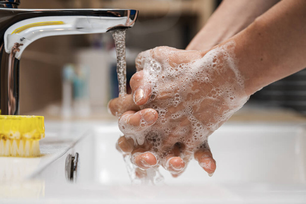 きれいな水道水の下で手を洗う女性のクローズアップビュー泡石鹸の多くを使用して. - 写真・画像