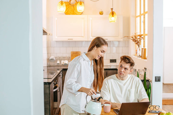 attractive lady pouring tea to working husband - Zdjęcie, obraz