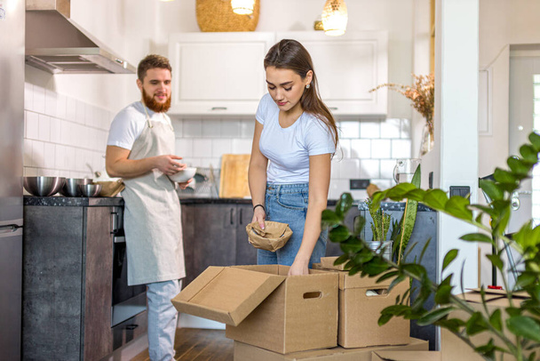 young happy couple unpacking cardboard boxes after moving in new house - Foto, imagen
