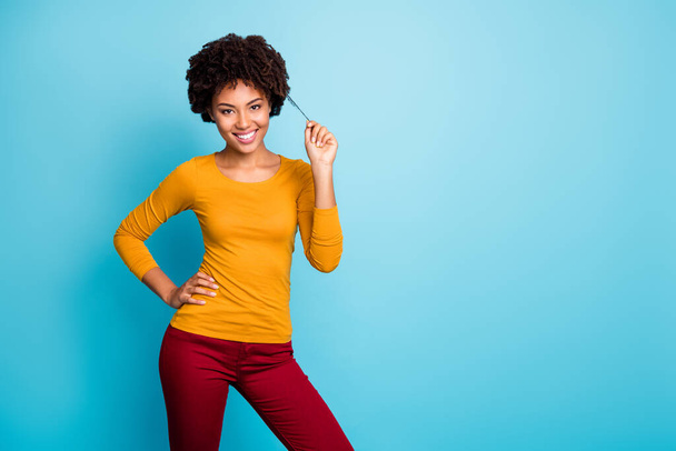 Portrait of charming lovely attractive afro american millennial girl enjoy autumn free time holidays touch her brunette curl wear good look outfit isolated over blue color background - Foto, afbeelding