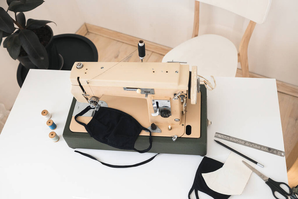 Бежевая швейная машинка Процесс шитья защитной медицинской маски в домашних условиях выполнен вручную в пастельных светлых тонах
 - Фото, изображение