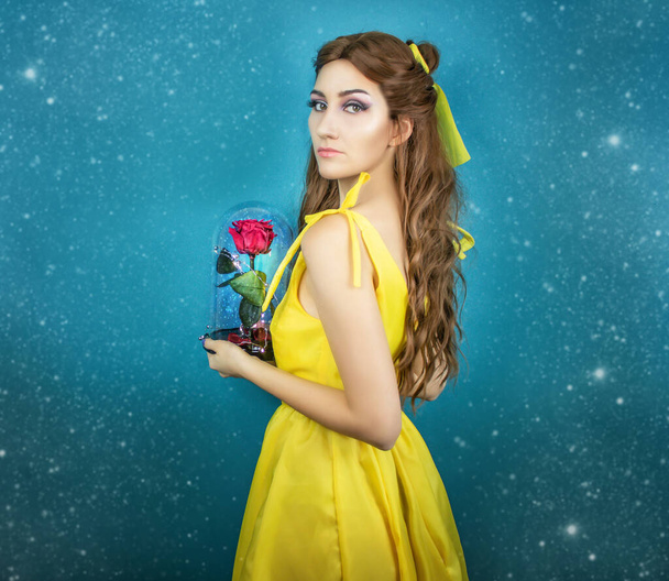 Pretty woman in the yellow long dress closeup with red rose in her hands. Beauty and the beast cosplay art processing - Foto, immagini