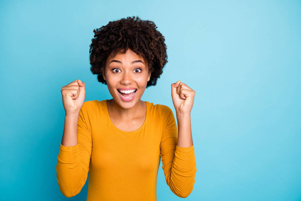 Portrait of excited astonished afro american girl look watch lottery wait for her victory raise fists scream impressed wear style stylish trendy jumper isolated over blue color background - Foto, Imagen