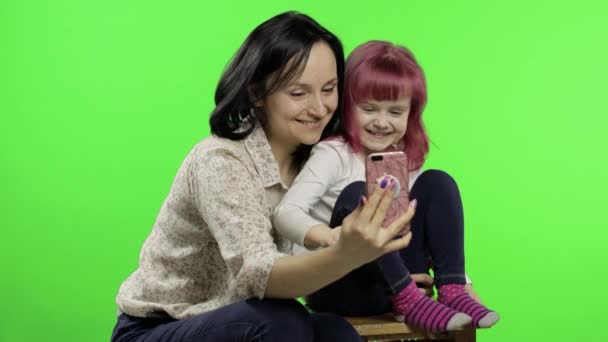 Madre, hija sosteniendo, usando el teléfono inteligente hablando en video llamada. Redes sociales
 - Imágenes, Vídeo