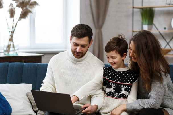 Quédate en casa. Retrato de una familia sonriente usando un portátil para una reunión en línea, videollamada, videoconferencia con padres, niños, parientes. Autoaislamiento. Pasar tiempo en casa en período de cuarentena - Foto, imagen