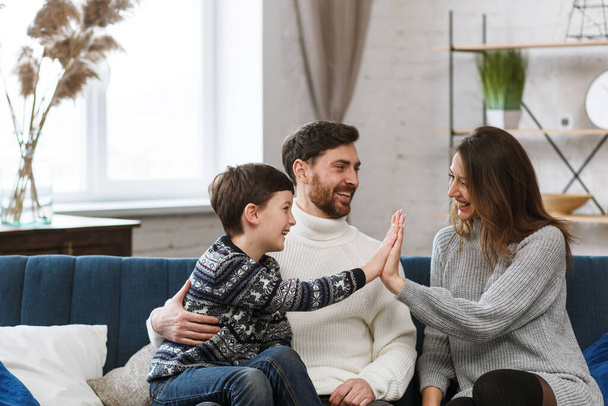 Portrait of smiling father, mother and son. Happy family spending time together at home. Cute boy with mom and dad playing at home. Time to family leisure. Family values - Photo, image