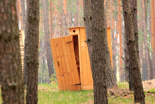 Une toilette extérieure en bois avec porte cassée
 - Photo, image
