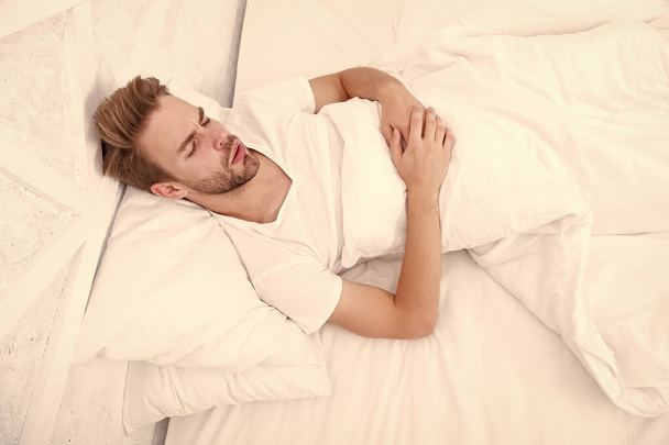 ベッドで寝ろ。朝早く起きろ!。白い寝室で寝てる男。居心地の良い週末だ。リラックスする時間だ。寝てろよ。男性の健康概念です。夢を見てる。平和の概念 - 写真・画像