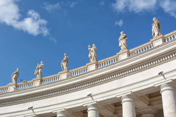 Vatican city, Vatican, Italy - April 18, 2017: The roof of Maderno's Facade of Saint Peter's Basilica, features statues of Jesus and Apostles along with John the Baptist jn background of a blue sky - Fotografie, Obrázek