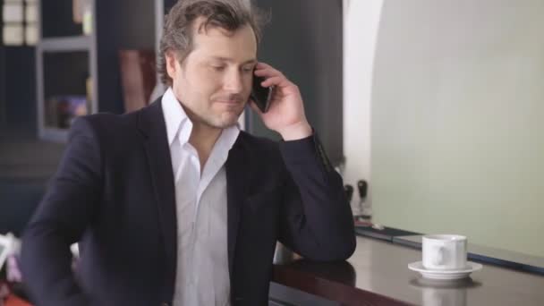 Businessman in business clothes speaks on the phone near the bar and drinks coffee - Video