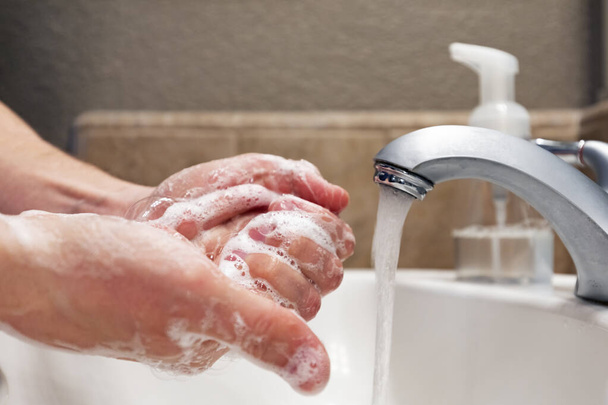 Käsien pesu saippualla ja vedellä kylpyhuoneen pesualtaassa, suojaus covid-19-koronaviruksen influenssaviruksilta, hygienia pysyä terveenä
 - Valokuva, kuva