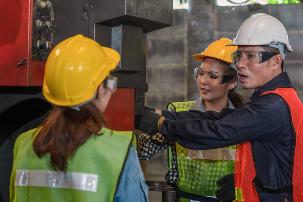 teollinen tausta aasialainen miespuolinen mekaanikko insinööri esimies selittää koneen työmenettely uusi naispuolinen mekaanikko insinööri metallityötä valmistus tehdas
 - Valokuva, kuva