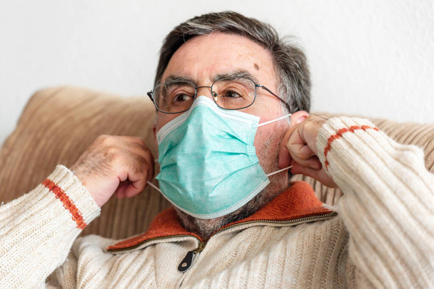 Homme âgé mettant un masque médical sur son visage pour se protéger contre la pandémie de coronavirus
.  - Photo, image