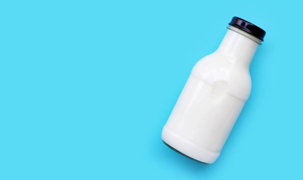 Μπουκάλι γάλακτος σε μπλε φόντο. Αντιγραφή χώρου - Φωτογραφία, εικόνα