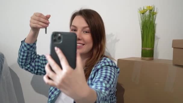 Young woman taking selfie on mobile phone. Moving new apartment home, boxes - Πλάνα, βίντεο