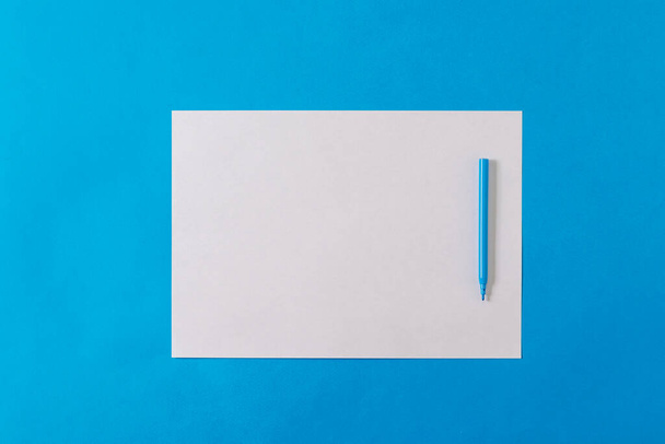 Синій маркер на білому аркуші паперу на синьому фоні. Мінімалізм
. - Фото, зображення