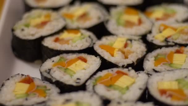 Αργή κίνηση του νόστιμα makizushi που με σολομό σερβίρεται σε λευκό πιάτο. Παραδοσιακό τυλιγμένο σούσι ιαπωνικό φαγητό στο εστιατόριο. Nori ρολό με σπορόφυτα ρυζιού και τα ψάρια σε ένα gourmet μενού -Dan - Πλάνα, βίντεο