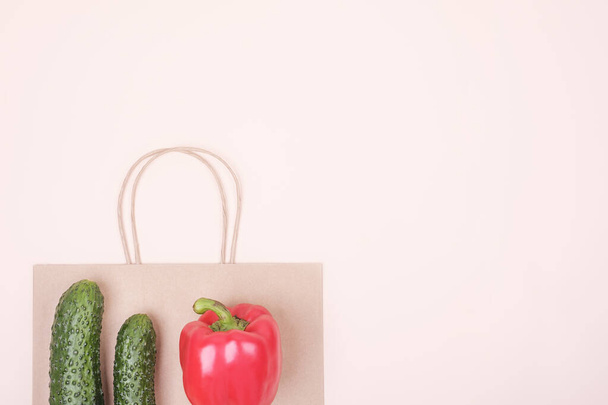 Świeże warzywa leżą na papierowej torbie na beżowym tle. Koncepcja zdrowego jedzenia. Widok z góry, przestrzeń kopiowania. - Zdjęcie, obraz