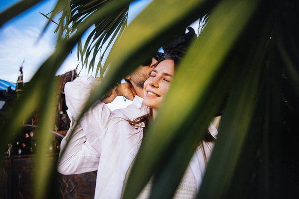 couple in love hugs and has fun on a romantic walk on the exotic island of Bali in Indonesia near palm trees - Photo, Image