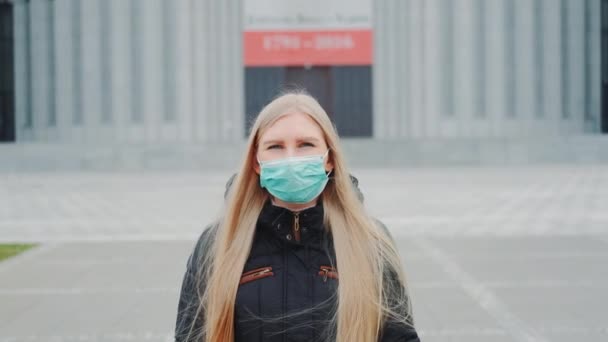 Mediana toma de mujer rubia en una máscara médica caminando por la calle
 - Imágenes, Vídeo