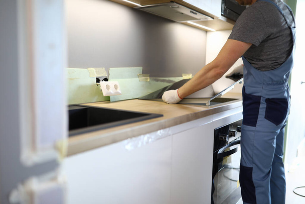 Reparateur installeert kookplaat keukentafel in appartement - Foto, afbeelding