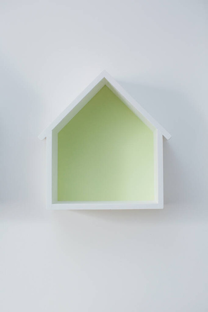 Empty house shaped shelf on a white wall. Decoration in kids room - Foto, imagen