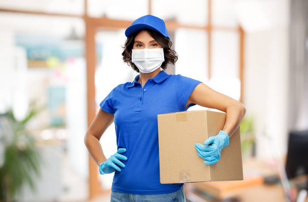 delivery girl in mask holding parcel box at office - Foto, afbeelding