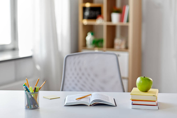 books, apple and school supplies on table at home - Foto, imagen