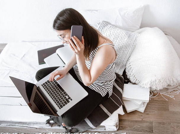 Een jonge vrouw werkt op afstand op een computer thuis. Freelancer en werken op het internet. - Foto, afbeelding