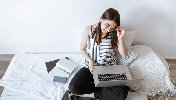 Eine junge Frau arbeitet zu Hause ferngesteuert am Computer. Freiberufler und Arbeit im Internet. - Foto, Bild