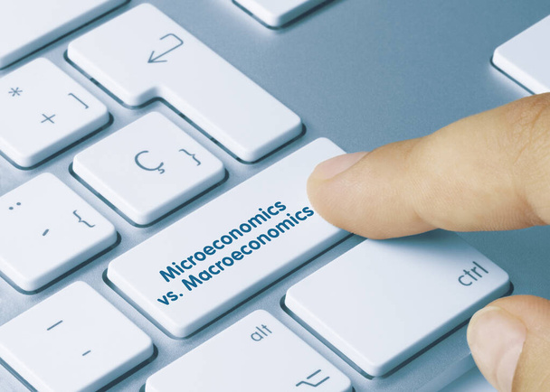 Micro-economie vs. Macro-economie Geschreven op Blauwe Sleutel van Metallic Keyboard. Vingertoets indrukken. - Foto, afbeelding
