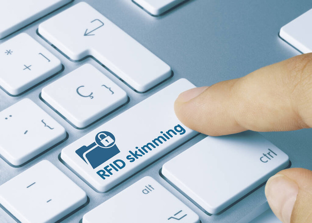 RFID skimming Written on Blue Key of Metallic Keyboard. Finger pressing key - Photo, Image