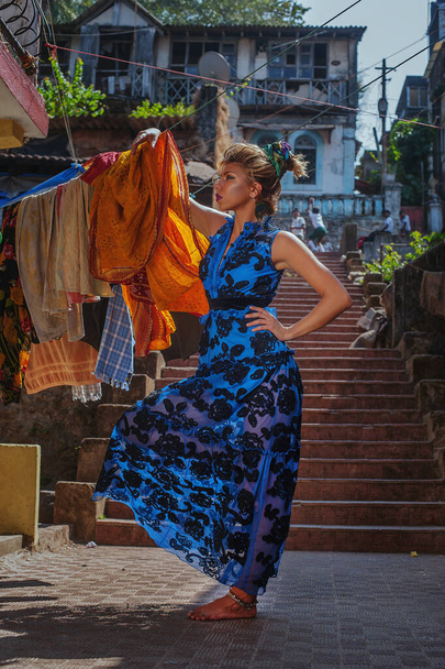 menina em um vestido bonito azul brilhante em um fundo da rua velha da cidade indiana velha, posando contra o fundo da lavanderia
. - Foto, Imagem