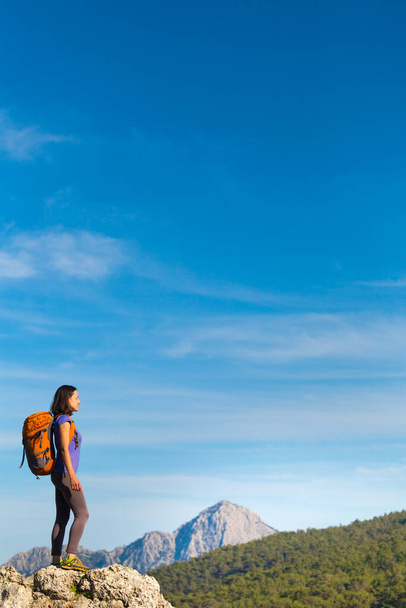 Una mujer con una mochila se encuentra en la cima de una montaña y admira la belleza de un valle de montaña, La chica viaja a lugares hermosos, Alcanzando la meta. Hermoso paisaje. - Foto, Imagen