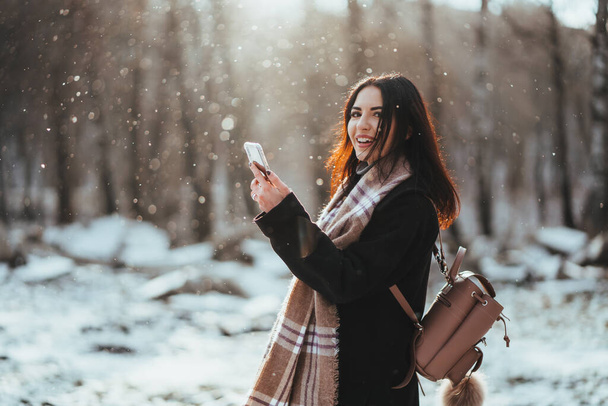 Жінка розмовляє по мобільному телефону. Усміхнена дівчина розмовляє на мобільному телефоні в холодний зимовий день
. - Фото, зображення