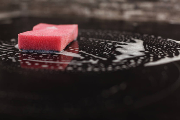 Fregona rosa usada izquierda en una superficie de cocina de cerámica cubierta de espuma en proceso de limpieza
 - Foto, Imagen