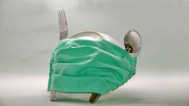 talheres, colheres e garfos dada uma máscara de saúde verde, Sem foco, Ruído, imagem de foco seletivo embaçado
 - Foto, Imagem