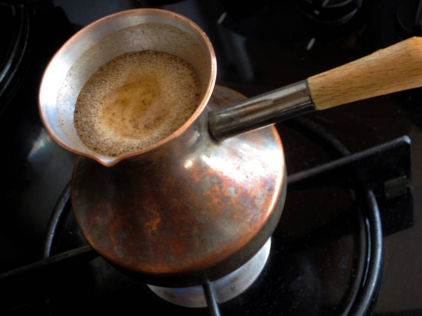 Barista preparing hot tasty drink from copper turk, boils water for coffee on small fire in cezve. Coffee turk made of organic copper, cezve to kitchen. Copper turk for real gourmet coffee at cezve. - Photo, Image