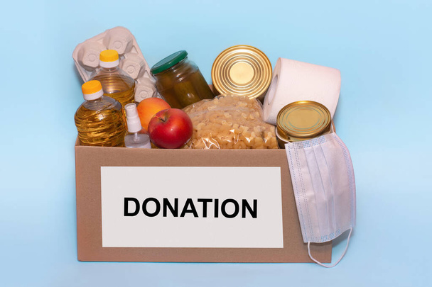 Еда в коробке для пожертвований, изолированная на синем фоне, копировальное место. Фонды коронавируса и пожертвования. Благотворительные пожертвования. Пожертвования в продовольственный банк
 - Фото, изображение
