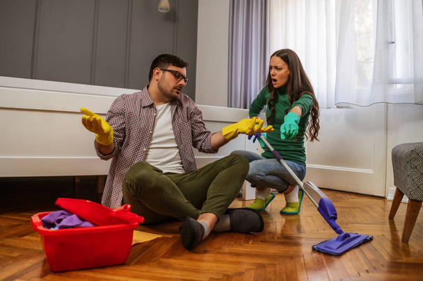 男は怠け者だ。彼の妻は彼らのアパートを掃除し続けるように言っている.  - 写真・画像